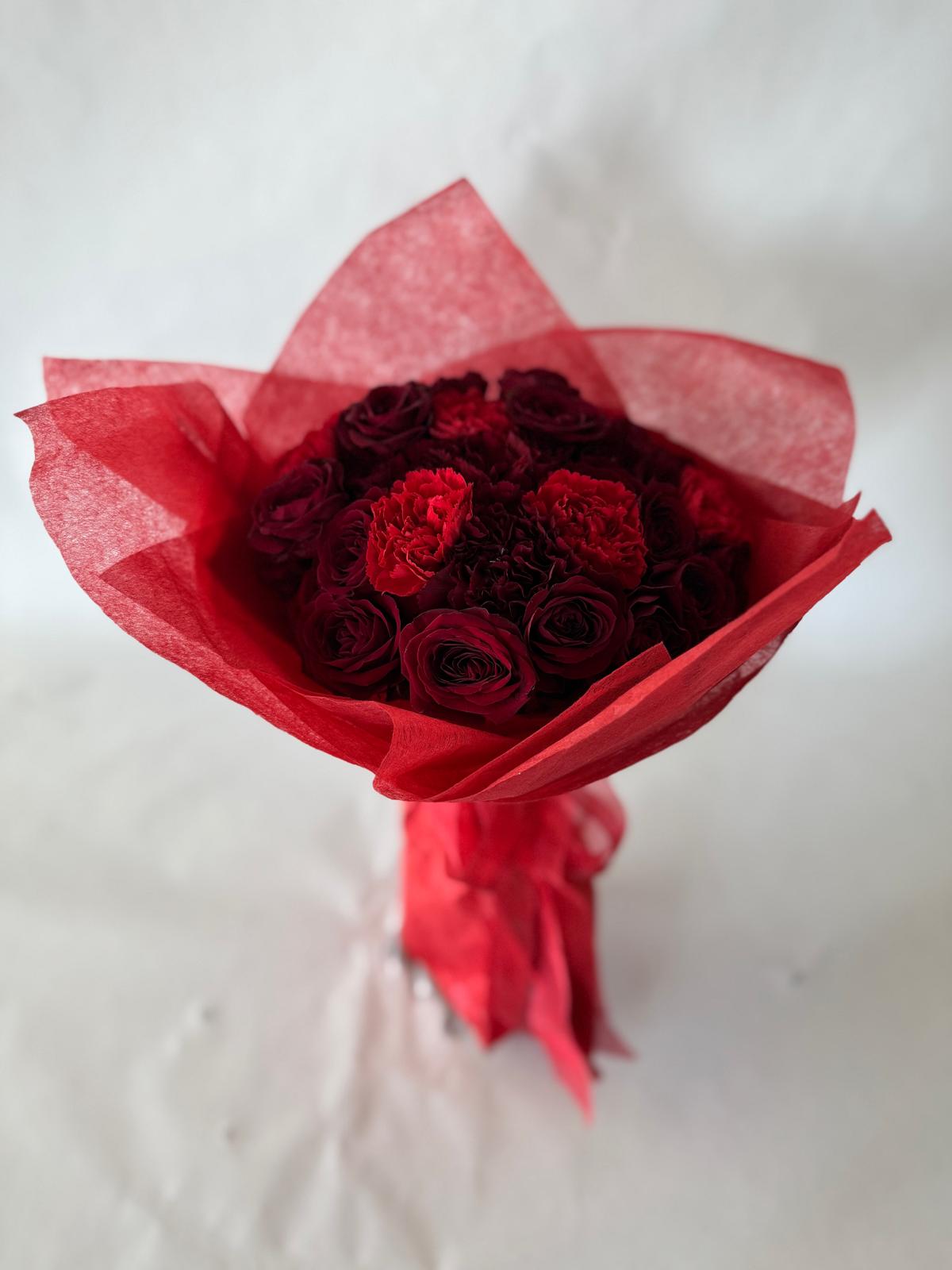 Red and burgundy bouquet with lush seasonal flowers and deep-toned wrapping.