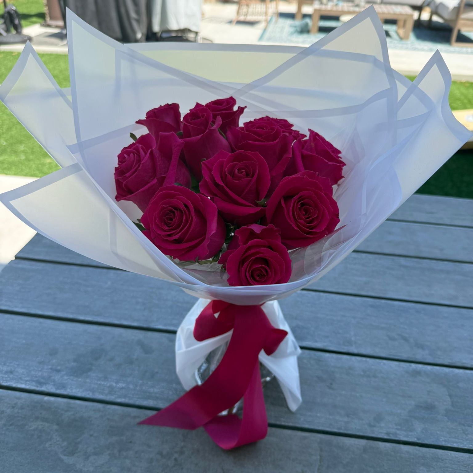 Bouquet of 12 hot pink roses wrapped in white paper with a satin ribbon.