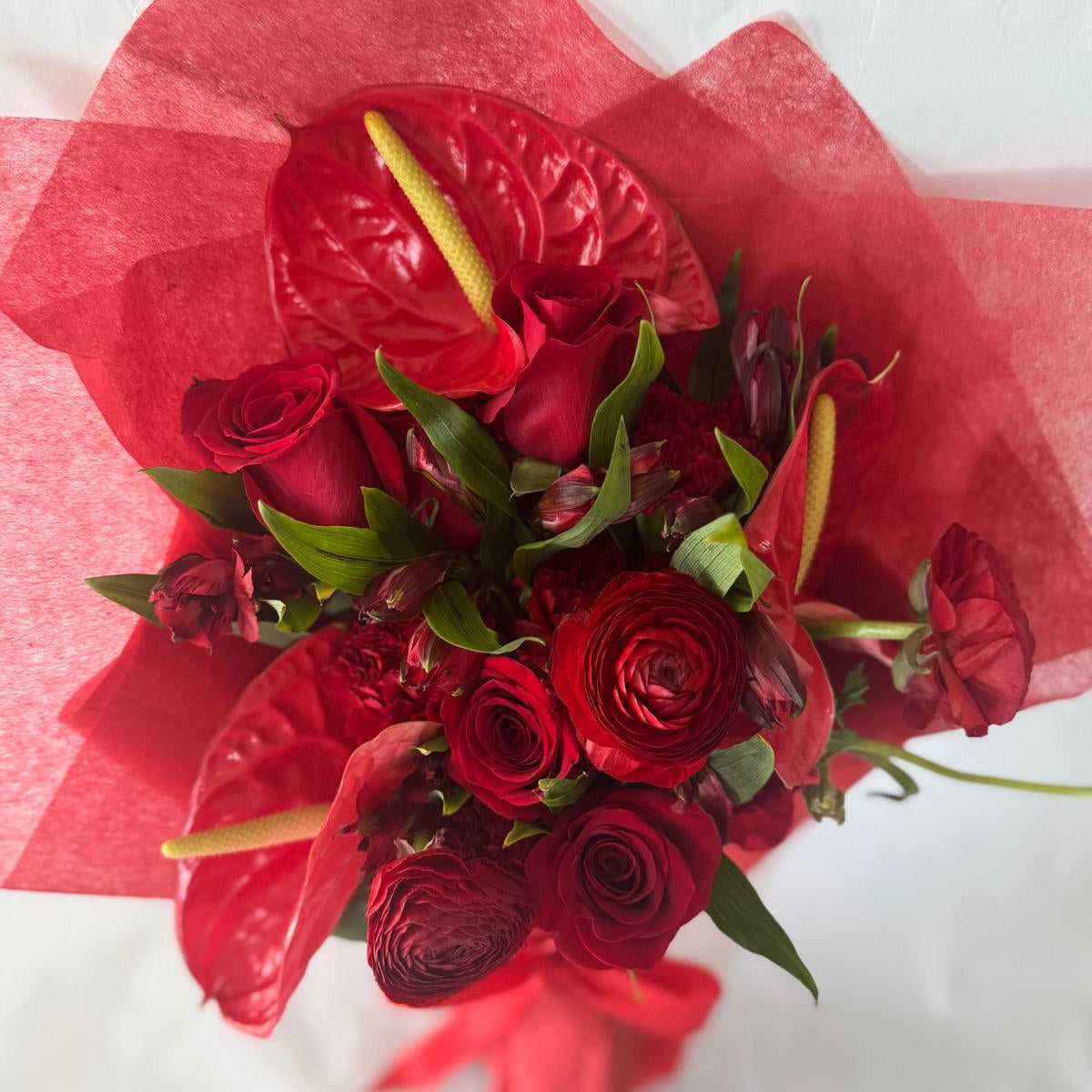 July Ruby bouquet from the Floral Gem Collection featuring an elegant arrangement of all-red blooms. A striking, floral-only design inspired by the deep, passionate tones of the ruby birthstone.