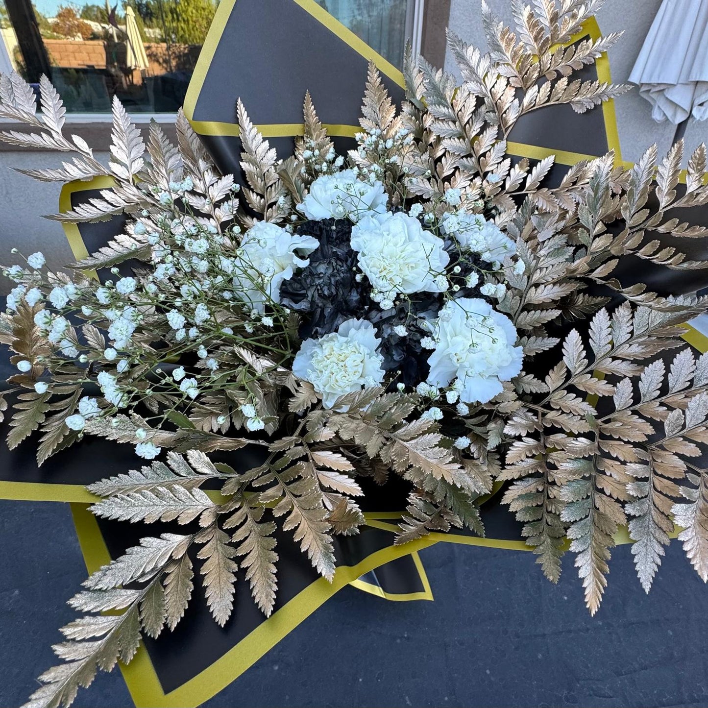 New Year’s Eve bouquet with white and black flowers, metallic gold ferns, and black-and-gold wrapping – Midnight Glam by Nai Pascoal Bouquets.