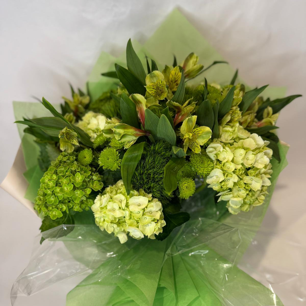 A vibrant green bouquet featuring soft lime and chartreuse blooms, inspired by the peridot birthstone and symbolizing growth and vitality.