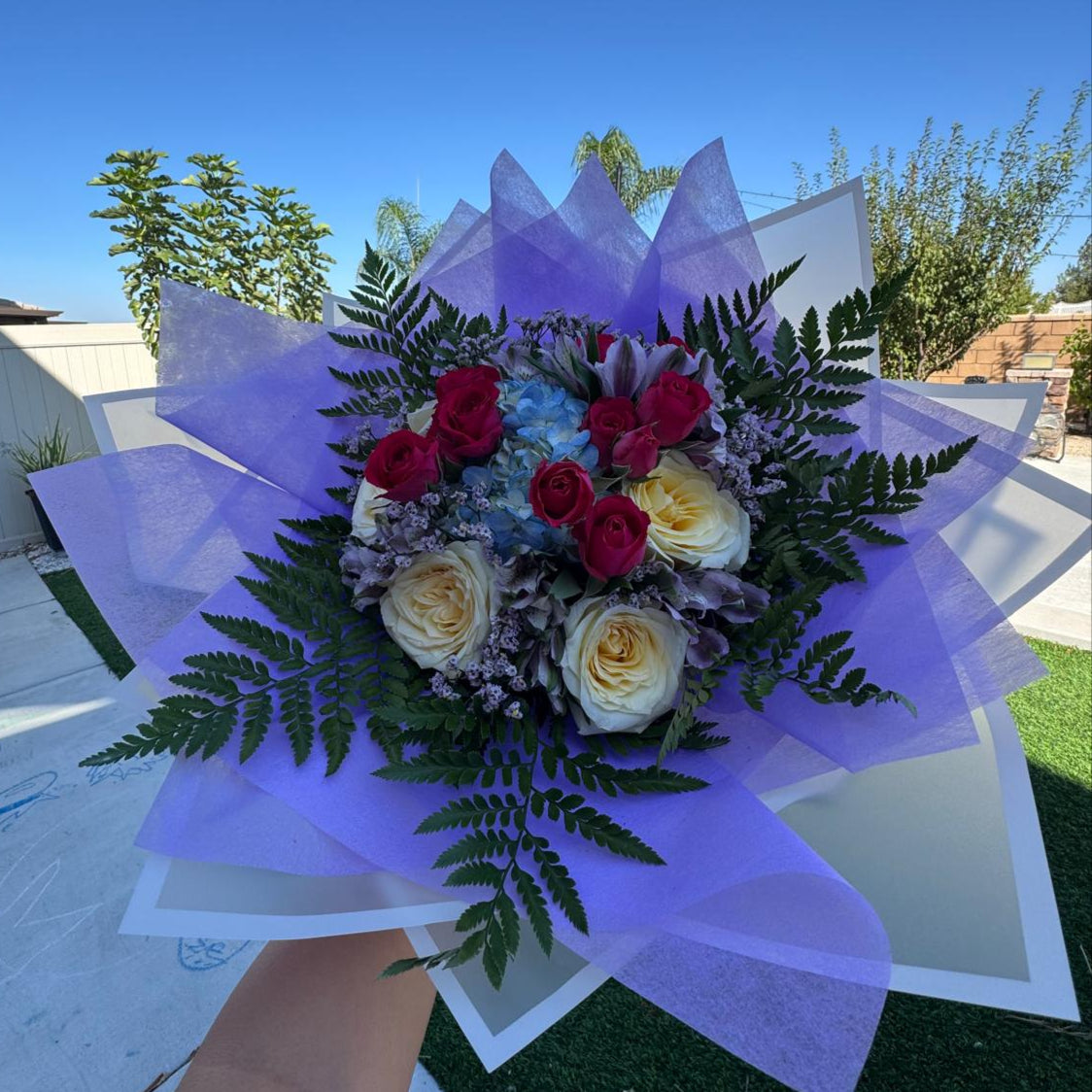 October Radiance bouquet inspired by opal and pink tourmaline, featuring jewel-toned and pastel blooms wrapped in lilac and white for a radiant autumn design.