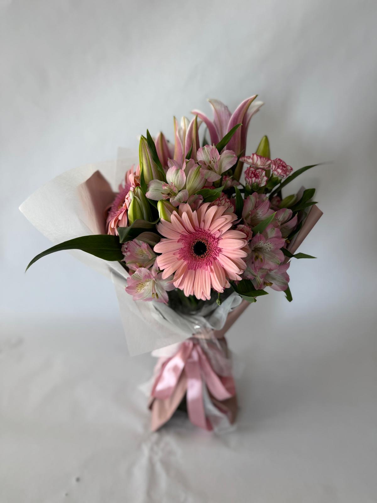 Blush pink bouquet with soft seasonal flowers wrapped in matching tones.