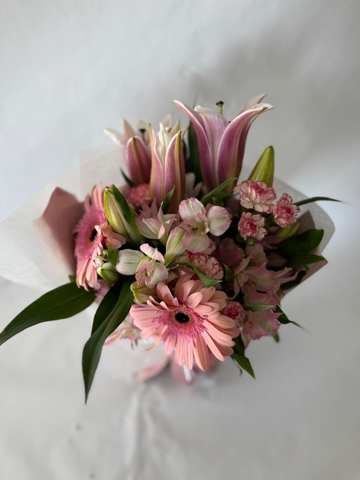 Blush pink bouquet with soft seasonal flowers wrapped in matching tones.