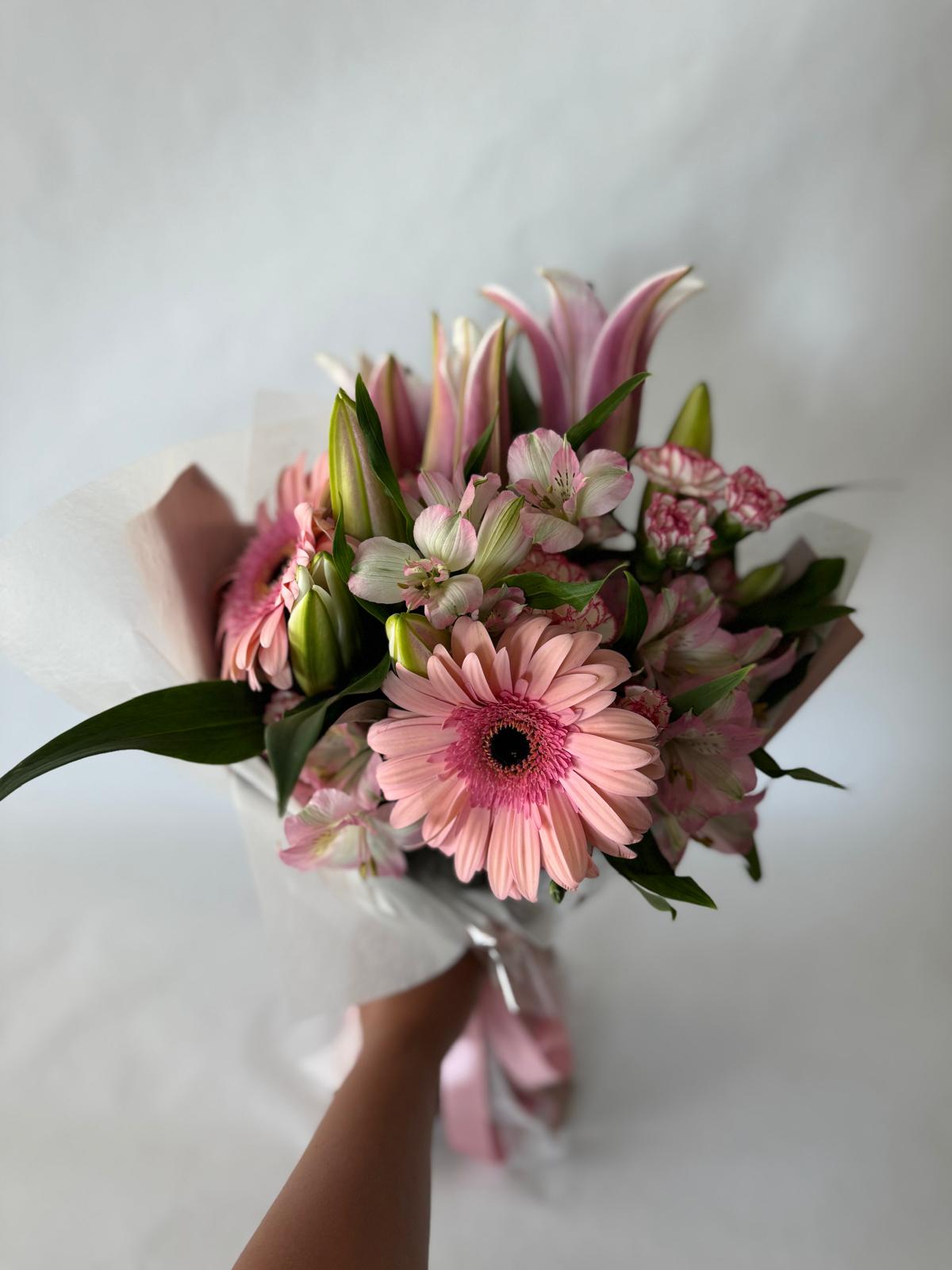 Blush pink bouquet with soft seasonal flowers wrapped in matching tones.