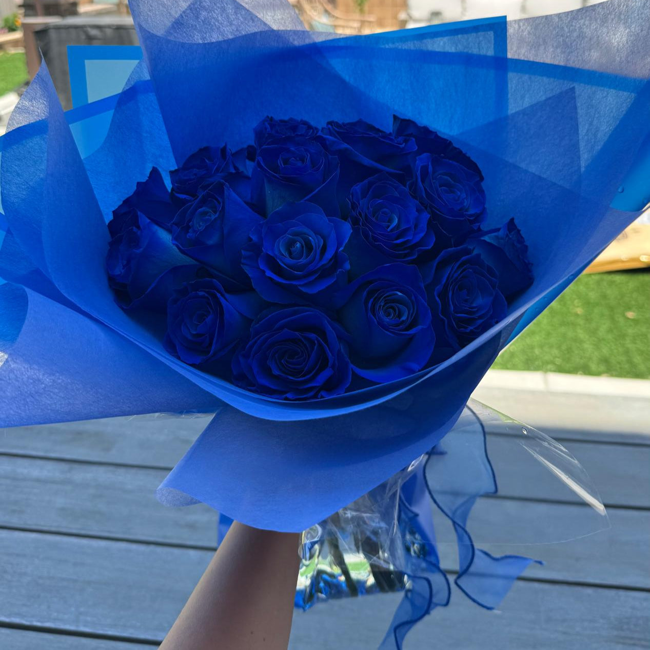 Hand-tied bouquet of deep sapphire-blue roses wrapped in blue matte paper with a satin ribbon.