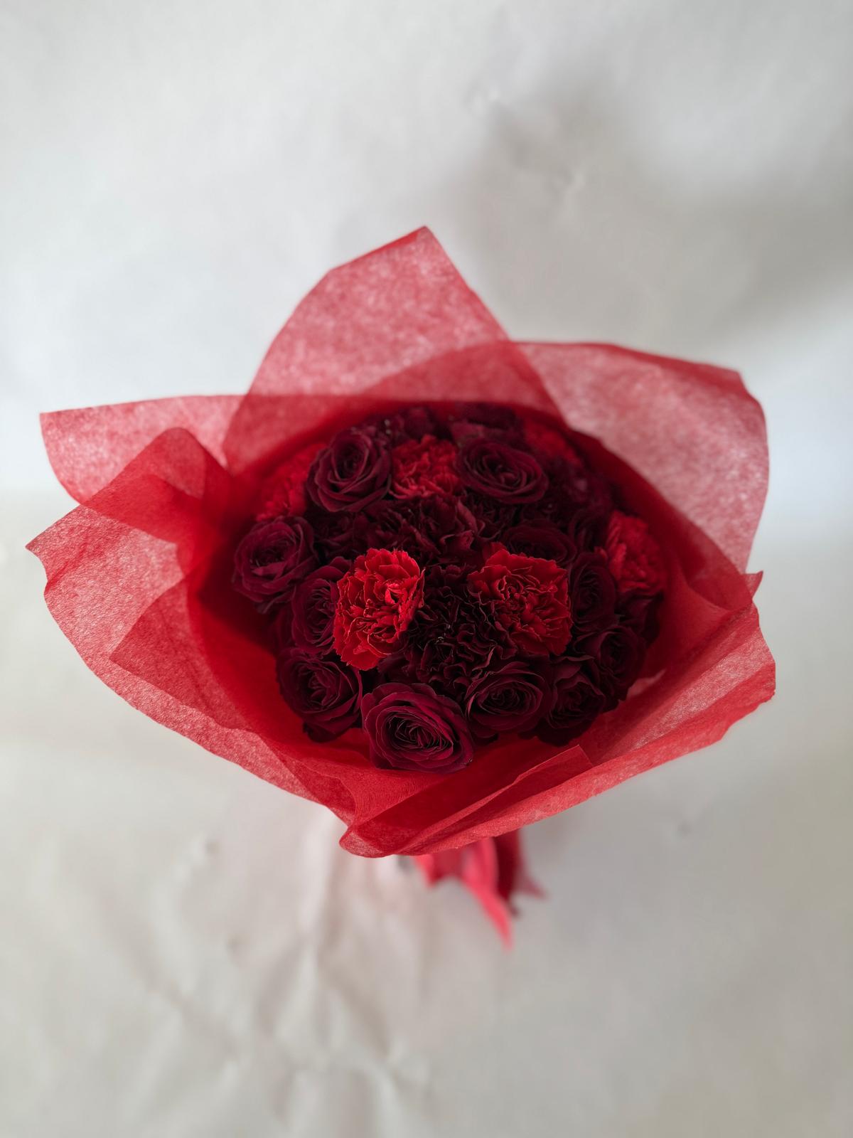 Red and burgundy bouquet with lush seasonal flowers and deep-toned wrapping.