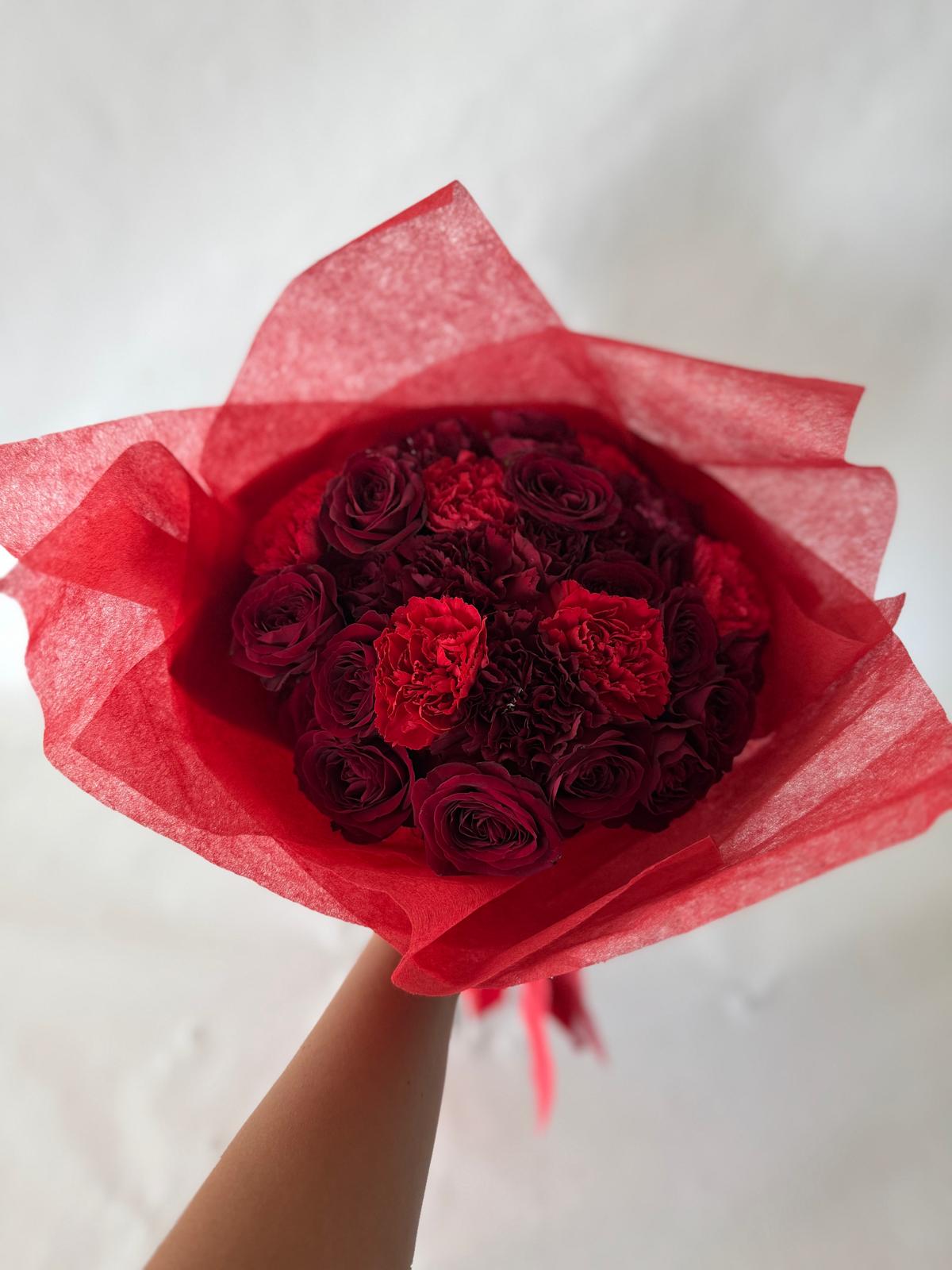 Red and burgundy bouquet with lush seasonal flowers and deep-toned wrapping.