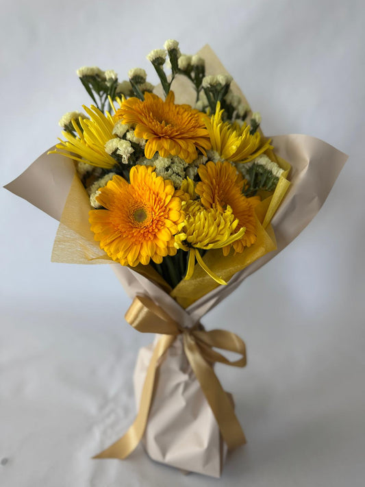Yellow bouquet with bright, sunlit flowers in soft butter and lemon tones, hand-wrapped in signature floral paper.