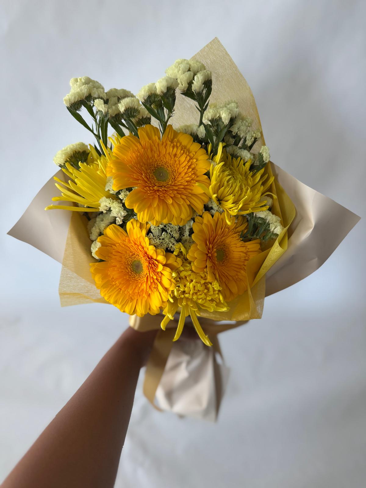 Yellow bouquet with bright, sunlit flowers in soft butter and lemon tones, hand-wrapped in signature floral paper.