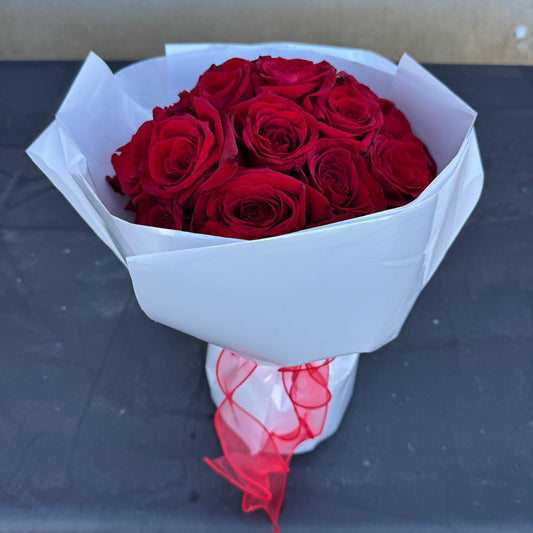 Classic red rose bouquet wrapped in white paper with a soft red ribbon.