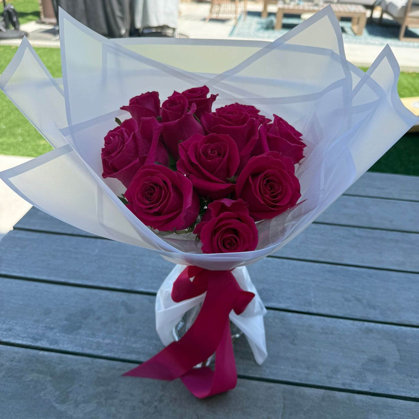 Bouquet of 12 hot pink roses wrapped in white paper with a satin ribbon.