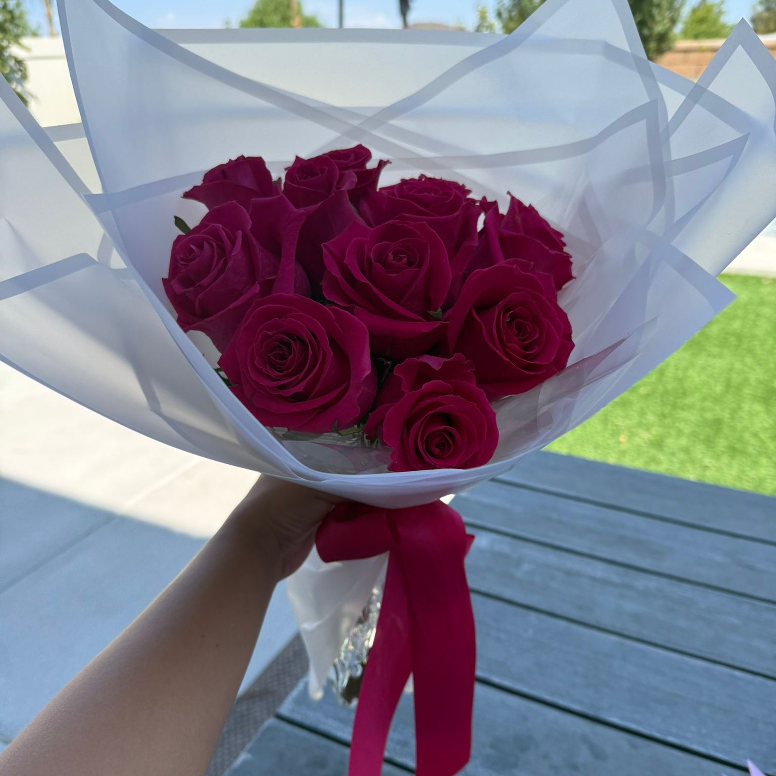 Bouquet of 12 hot pink roses wrapped in white paper with a satin ribbon.