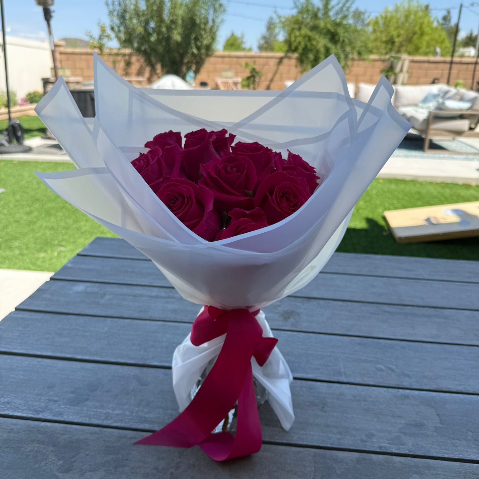 Bouquet of 12 hot pink roses wrapped in white paper with a satin ribbon.