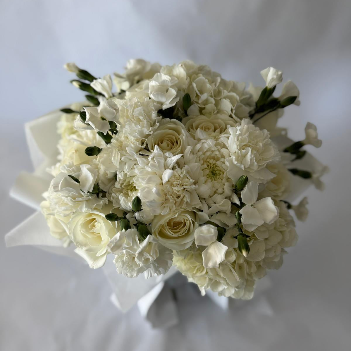 Full and lush floral-only bouquet in soft ivory tones with roses, carnations, and seasonal filler blooms, inspired by the June birthstone