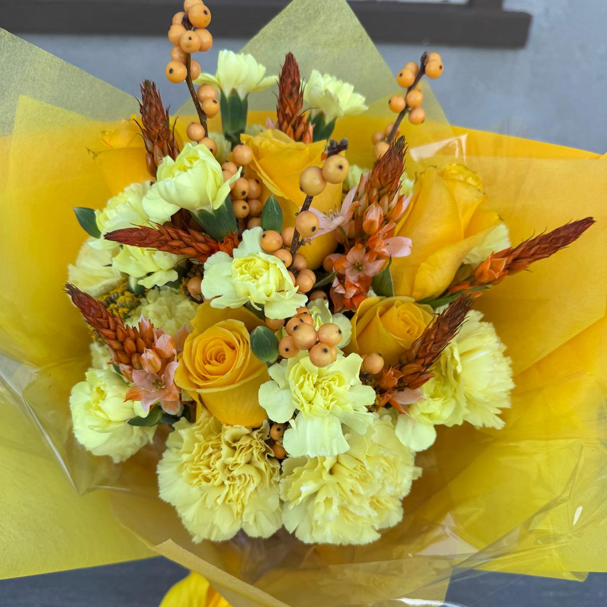 November Glow Bouquet inspired by Citrine & Topaz birthstones, featuring golden yellow roses, amber accents, and autumn textures wrapped in golden paper.