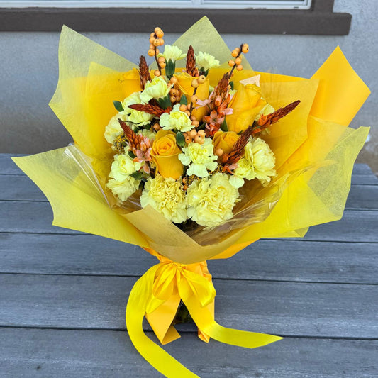 November Glow Bouquet inspired by Citrine & Topaz birthstones, featuring golden yellow roses, amber accents, and autumn textures wrapped in golden paper.