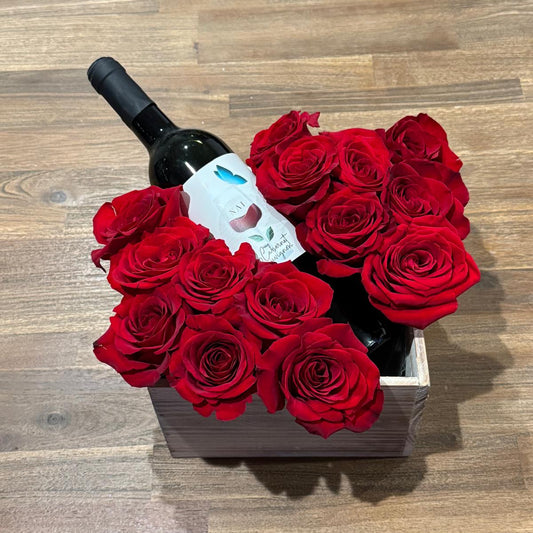 A romantic Valentine’s arrangement featuring premium red roses styled around a wine bottle in a keepsake wooden box. Handcrafted and available for local delivery.