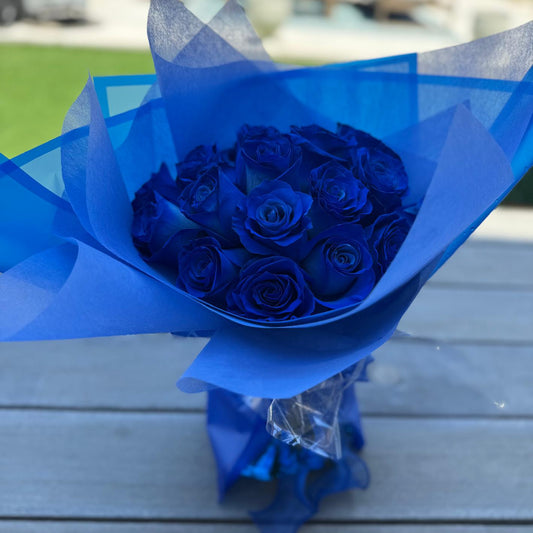 Hand-tied bouquet of deep sapphire-blue roses wrapped in blue matte paper with a satin ribbon.