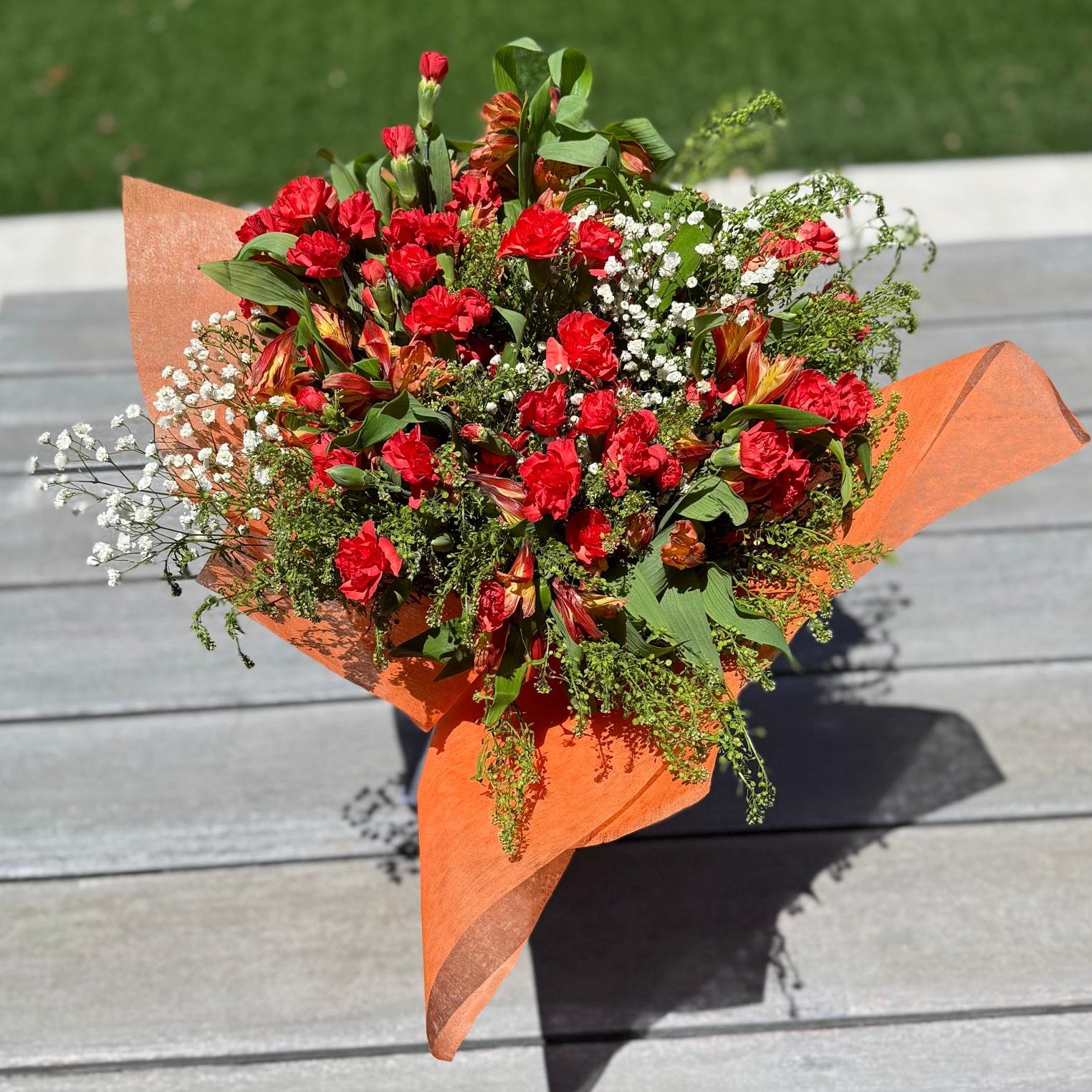 Handcrafted orange floral arrangement with filler blooms only