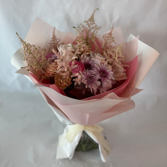 A gentle bouquet in warm blush and rose tones, softly wrapped in pink and cream, offering warmth and compassion during moments of grief.