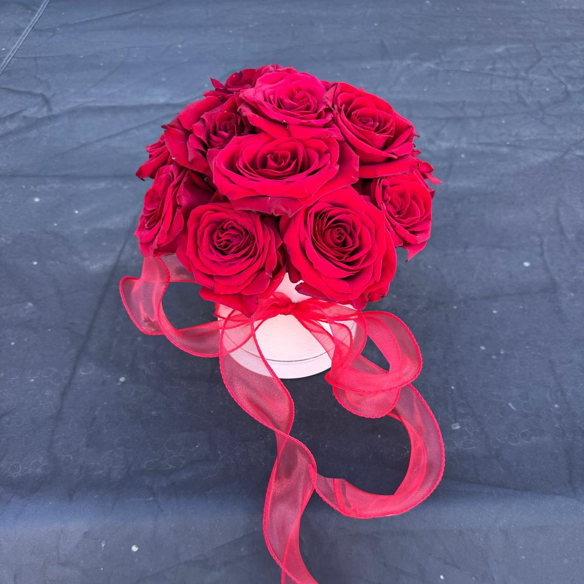 Red rose Valentine’s Day arrangement in a round box with a sheer red ribbon.
